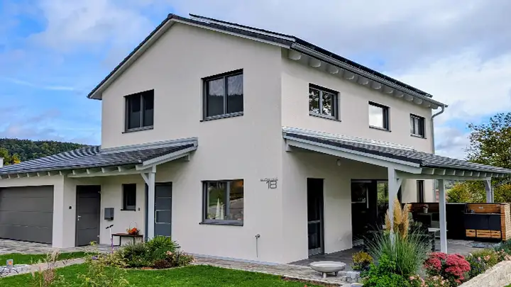 Beigefarbenes Einfamilienhaus mit Satteldach, Eingangsüberdachung sowie Terrassenüberdachung