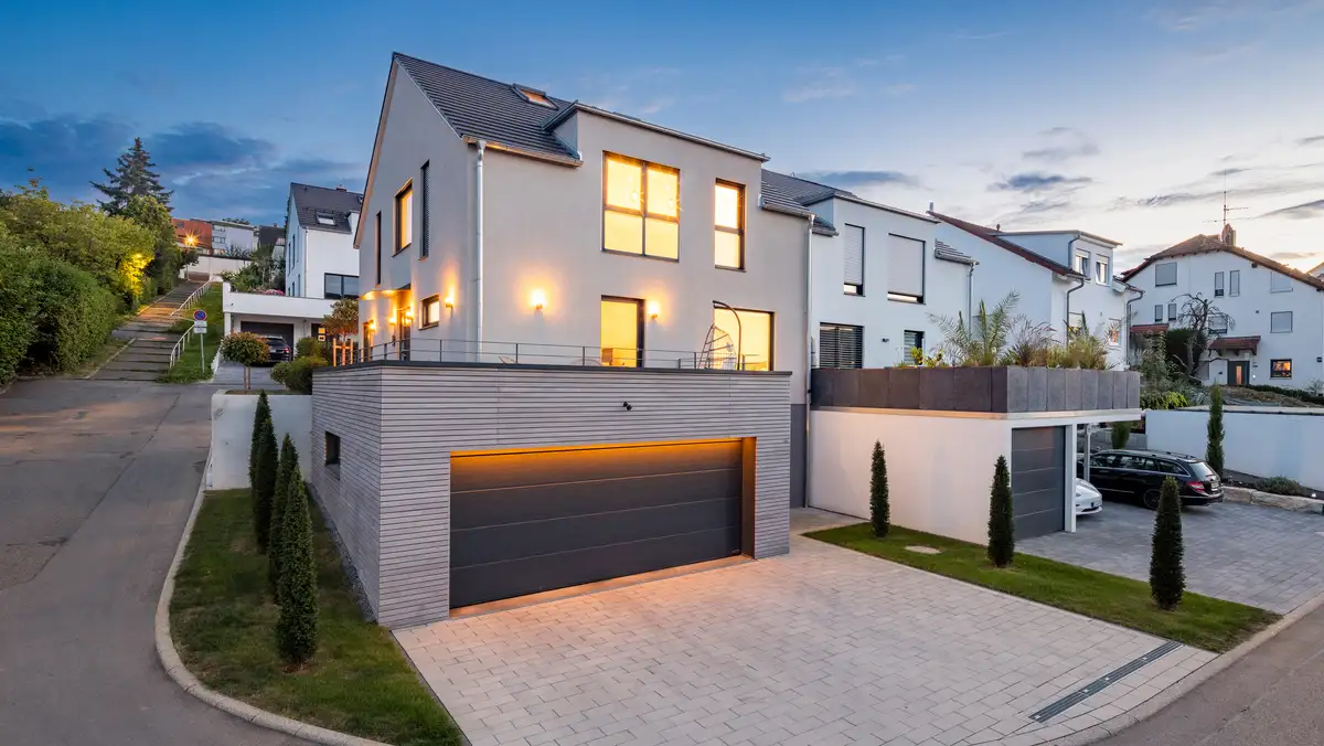 Doppelhaus in Hanglage - die Garage ist im Hang eingebunden, das Doppelhaus nutzt die Hanglage optimal aus - Blick von der Straßenseite auf die moderne Doppelhaushälfte mit Holzdetails