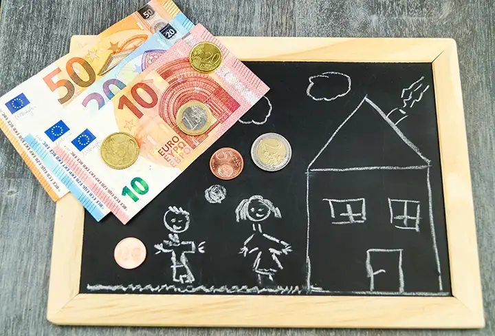 Kleine Tafel mit einem Haus, einer Familie und Bargeld als Symbol für die Familieförderung